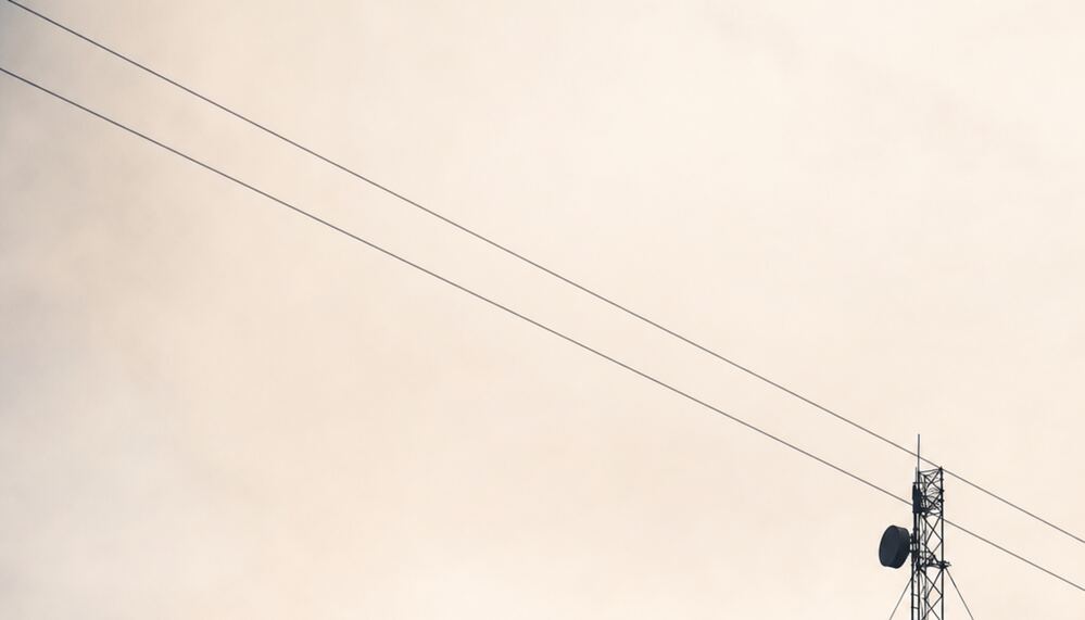 Communications mast silhouetted against a pale dawn sky.